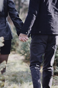 a man and a woman holding hands in a wooded area