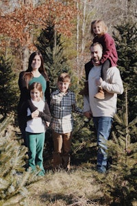 a family posing in front of a christmas tree farm