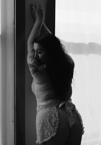 a woman in a lingerie posing in front of a window