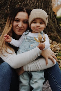 a woman holding a baby in front of a tree