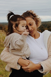 a woman holding a child in a field