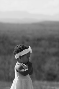 a black and white photo of a little girl in a white dress