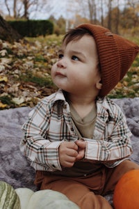 a baby sitting on a blanket with pumpkins