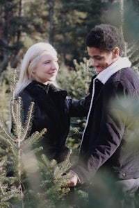 a couple is holding hands in a christmas tree field