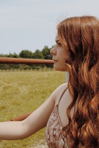 a woman with long red hair standing in a field