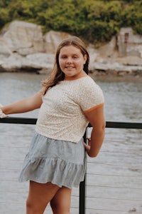 a girl posing on a railing near a body of water