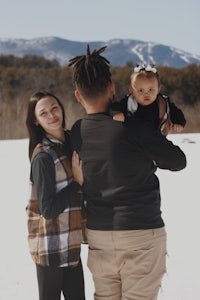 a man and woman holding a baby in the snow